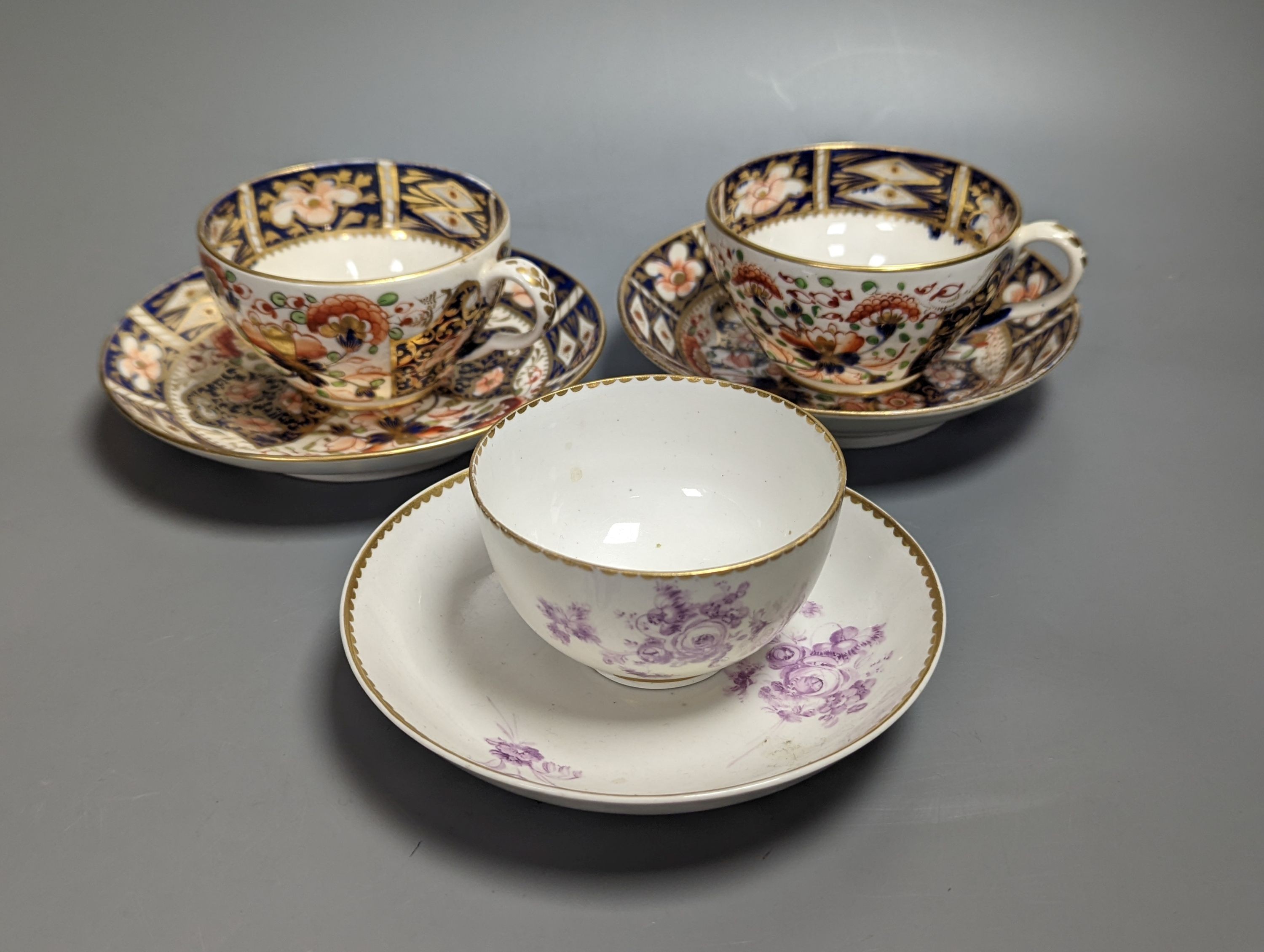 Two Derby imari pattern tea cups and saucers and a Derby teabowl and saucer painted in puce, each with three sprays of flowers, c.1785 and later